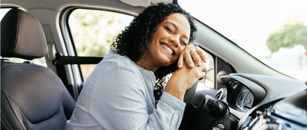 Young woman hugging her steering wheel