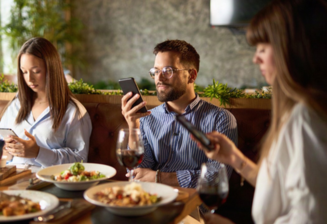 A group of three people out to dinner on their phones