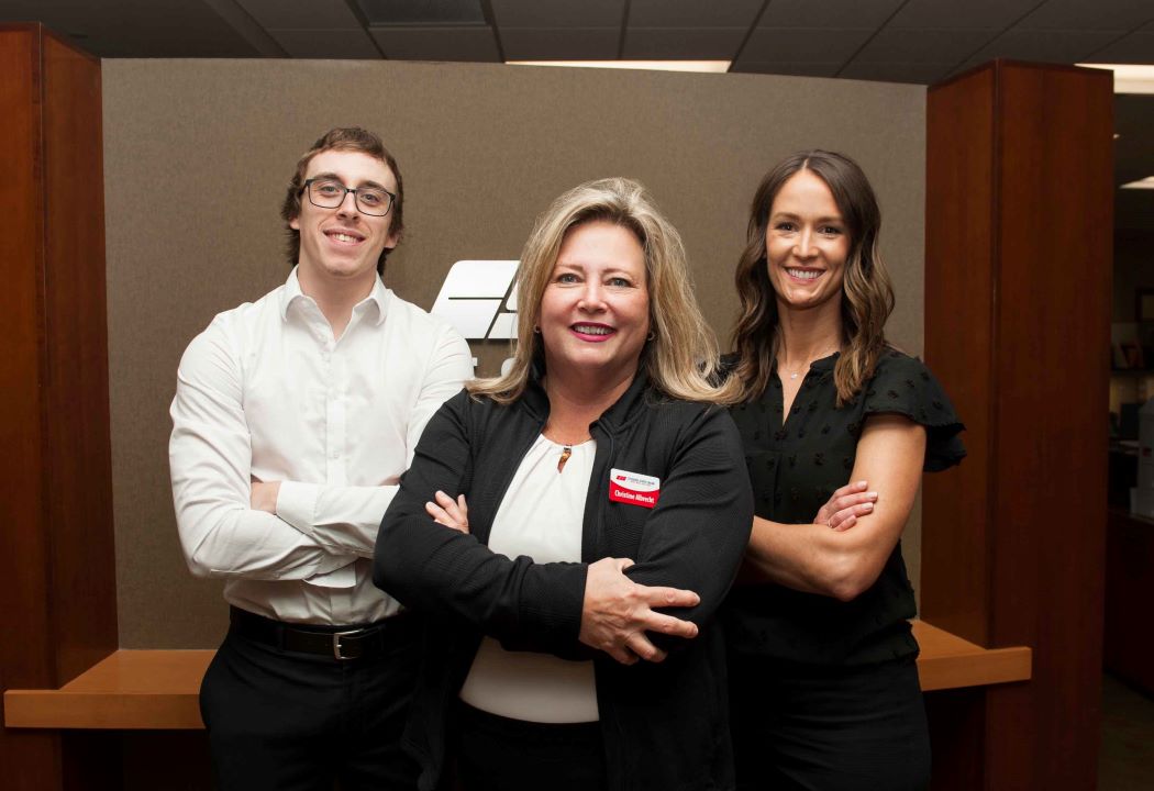 2 ladies and one young man standing in the lobby of a bank