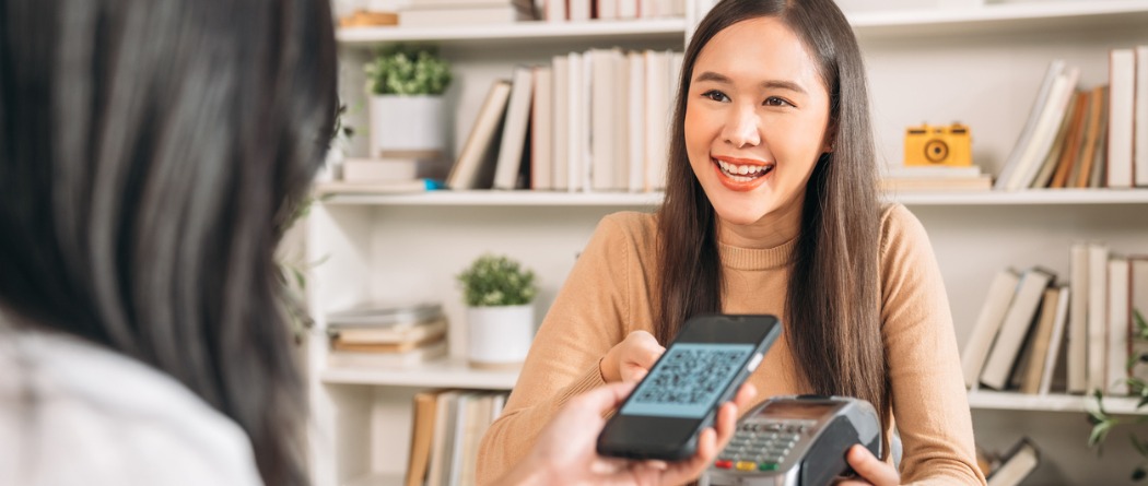 a lady holding a phone to pay for her book