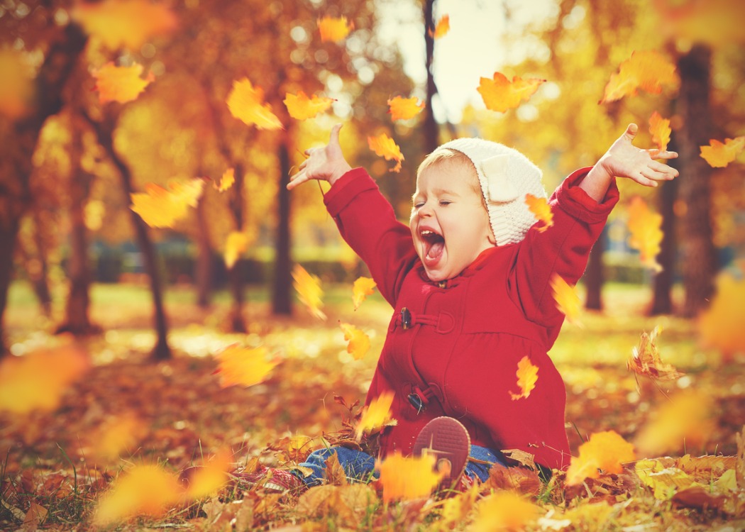 Little girl playing in fall leaves