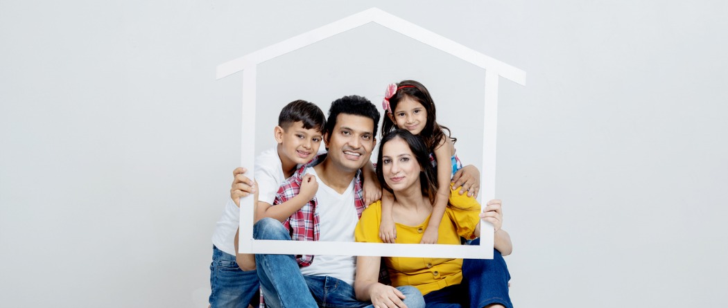 A family looking through a house shaped picture frame