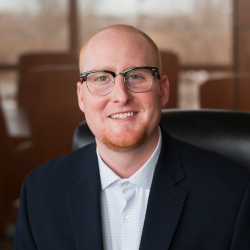 A young man in business style dress is sitting in an office chair.