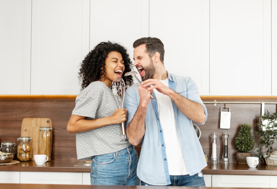 Happy interracial couple singing in the kitchen.