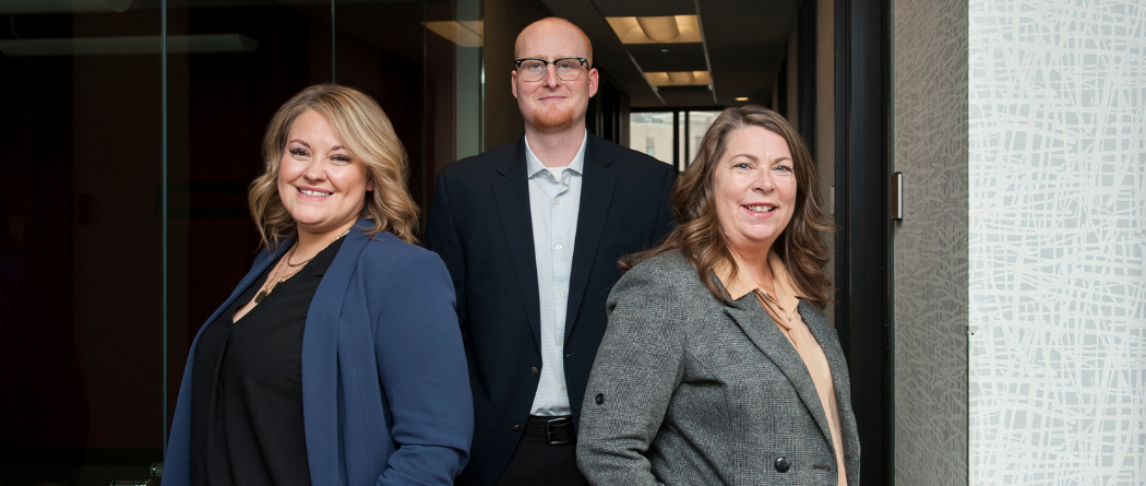 A young woman, Tava, a tall man, Kincaid and another woman, Shery are all standing together in a hallway.
