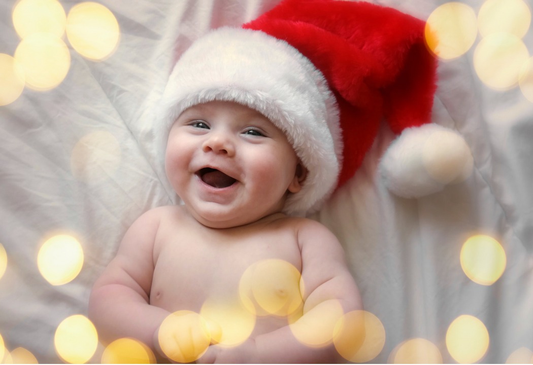 A baby in a Santa hat is so happy for the holidays. 