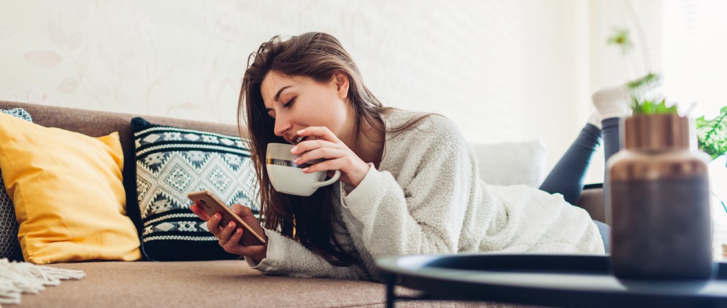 Young lady with a cup of coffee looking at her phone