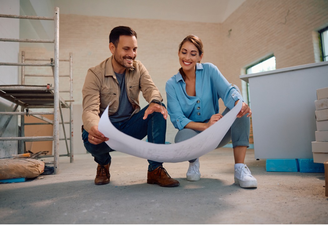 A couple looking at blue prints for building their home.